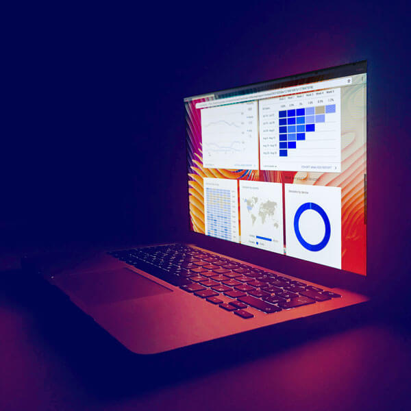 glowing screen of a laptop with report charts against a dark background